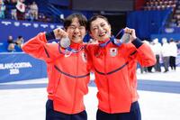 団体で獲得した銀メダルを掲げる男子の鍵山優真（左）と女子の坂本花織＝ミラノ（共同）