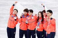 団体で銀メダルを獲得し日の丸を掲げる（左から）坂本花織、佐藤駿、鍵山優真、吉田唄菜、森田真沙也、三浦璃来、木原龍一＝ミラノ（共同）