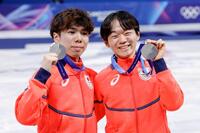 団体で獲得した銀メダルを掲げる男子の佐藤駿（左）と鍵山優真＝ミラノ（共同）