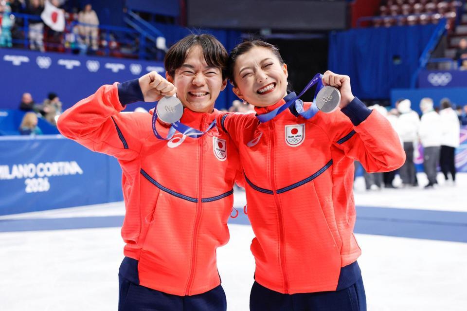 団体で獲得した銀メダルを掲げる男子の鍵山優真（左）と女子の坂本花織＝ミラノ（共同）