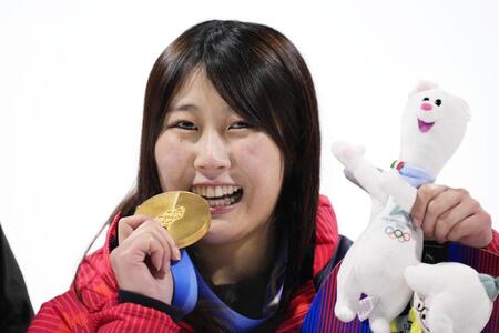 　女子ビッグエアで獲得した金メダルをかじるポーズで笑顔の村瀬心椛＝リビーニョ（共同）