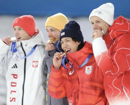 銅メダルを笑顔でかじる二階堂蓮（中央）＝プレダッツォ・ジャンプ競技場（撮影・吉澤敬太）