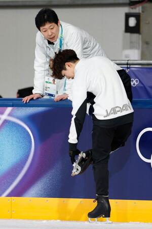 練習中に靴のブレードを気にするフィギュアスケート男子の佐藤駿。奥は日下匡力コーチ＝９日、イタリア・ミラノ（共同）