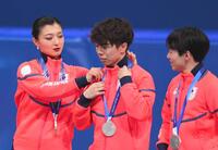 　表彰台で佐藤駿（中央）のメダルを整える坂本。右は鍵山