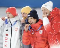 銅メダルを笑顔でかじる二階堂蓮（中央）＝プレダッツォ・ジャンプ競技場（撮影・吉澤敬太）