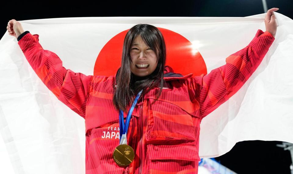 スノーボード女子ビッグエアで金メダルを獲得し、笑顔で日の丸を掲げる村瀬心椛＝９日、リビーニョ（共同）