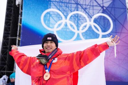 男子モーグルで銅メダルを獲得し日の丸を掲げる堀島行真＝リビーニョ（共同）