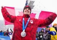 男子モーグルで銀メダルを獲得し、笑顔で国旗を掲げるミカエル・キングズベリー＝リビーニョ（共同）