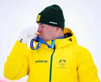 男子モーグルで獲得した金メダルにキスをするクーパー・ウッズ＝リビーニョ（共同）