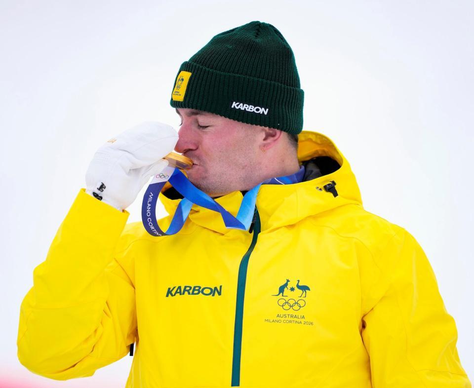 男子モーグルで獲得した金メダルにキスをするクーパー・ウッズ＝リビーニョ（共同）