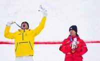 男子モーグルで金メダルを獲得したクーパー・ウッズ（左）に、拍手を送る銅メダルの堀島行真＝リビーニョ（共同）