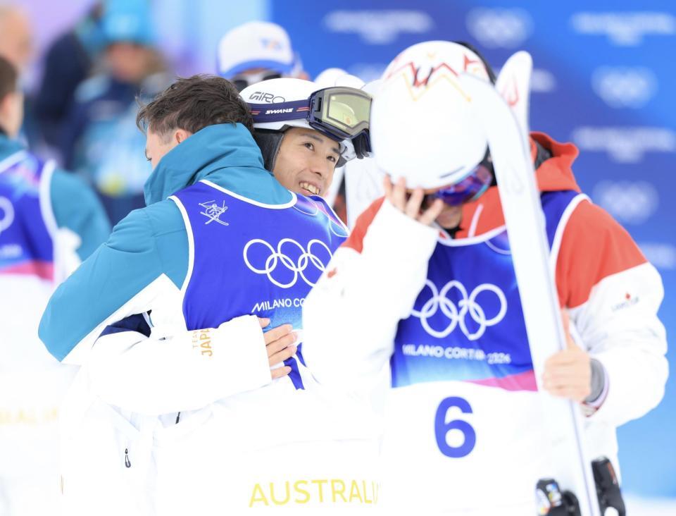 金メダルの豪州のウッズクーパーと抱き合う銅メダルの堀島行真。手前は肩を落とすカナダのキングズベリー＝リビーニョ・エアリアル・モーグルパーク（撮影・吉澤敬太）