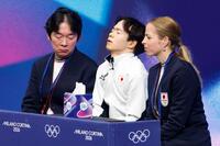 男子フリーの得点を確認し、目を閉じる鍵山優真。左は父の正和コーチ、右はカロリナ・コストナー・コーチ＝ミラノ（共同）
