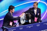 男子フリーの得点を確認し、顔を覆う鍵山優真。左は父の正和コーチ、右はカロリナ・コストナー・コーチ＝ミラノ（共同）