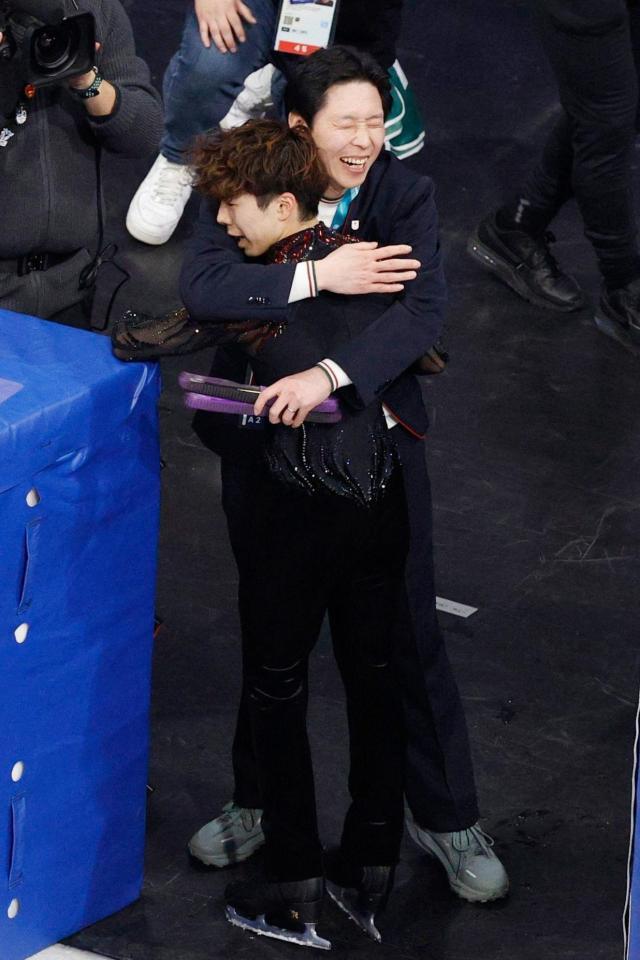 男子フリー演技を終え、日下匡力コーチ（奥）に迎えられる佐藤駿＝ミラノ（共同）