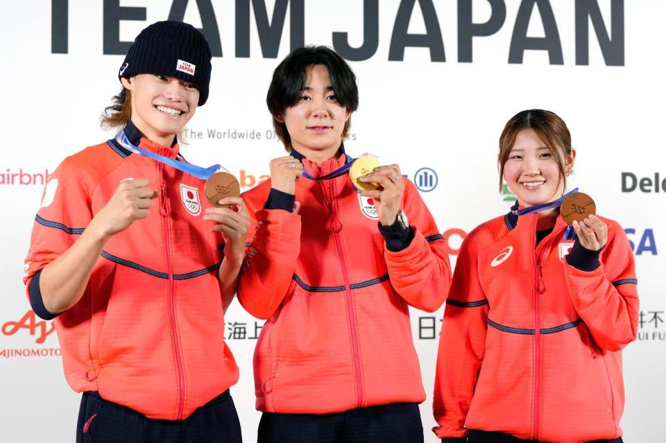 記者会見でメダルを掲げるスノーボード・ハーフパイプの（左から）山田琉聖、戸塚優斗、小野光希＝15日、イタリア・ミラノ（共同）