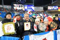 丸山希の母の遺影を持ち見つめる丸山希の父（中央）＝プレダッツォ・ジャンプ競技場（撮影・吉澤敬太）