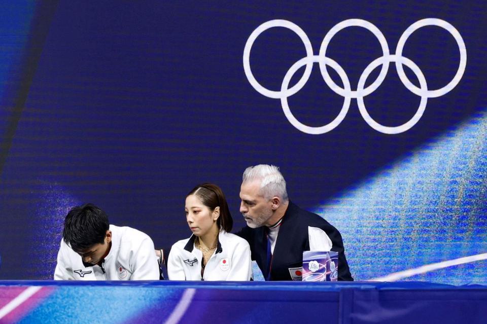 ペア・ＳＰの得点を確認し、肩を落とす三浦璃来（中央）、木原龍一組。右はブルーノ・マルコット・コーチ＝ミラノ（共同）