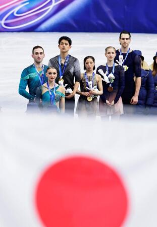 ペアで金メダルを獲得し、掲揚される日の丸を見つめる三浦璃来（中央右）、木原龍一（同左）組（共同）
