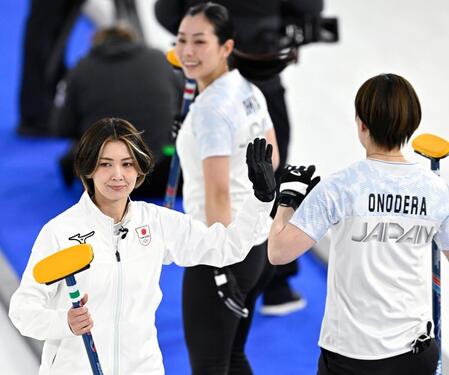 日本－イタリア　第１エンド、ショットを決めタッチを交わす吉村（左）＝コルティナダンペッツォ（共同）
