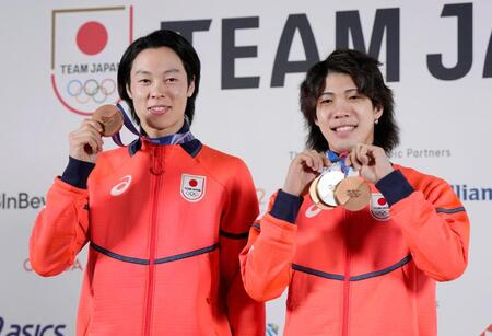 記者会見を終え、メダルを手にポーズをとるノルディックスキー・ジャンプ男子の小林陵侑（左）と二階堂蓮＝18日、イタリア・ミラノ（共同）