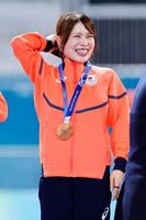 女子団体追い抜きで銅メダルを獲得し、表彰台で笑顔の佐藤綾乃＝ミラノ（共同）