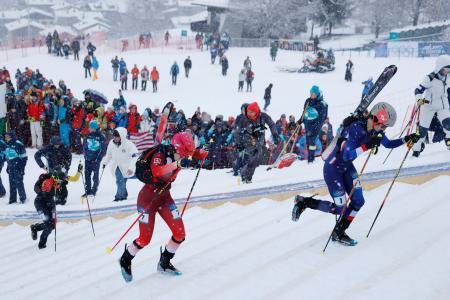 　山岳スキー女子スプリント予選で、スキー板を背負って力走する選手たち＝１９日、イタリア・ボルミオ（共同）