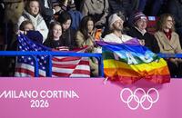 女子フリーでアンバー・グレンが紹介され、虹色の旗を掲げる人＝ミラノ（共同）