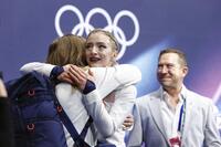 女子フリーの得点を確認し、関係者と抱き合うアンバー・グレン（中央）＝ミラノ（共同）