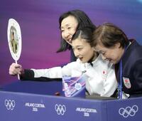 ミラノ・コルティナ五輪　キスアンドクライでうちわを差し出す坂本花織＝ミラノアイススケートアリーナ（撮影・吉澤敬太）