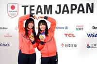 　記者会見でメダルを掲げるスノーボード女子の深田茉莉（左）と村瀬心椛（共同）