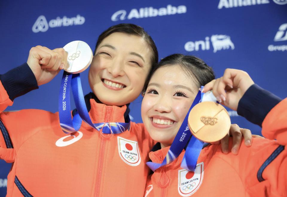 ミラノ・コルティナ五輪　笑顔でメダルを掲げる中井亜美（右）と坂本花織＝ミラノアイススケートアリーナ（撮影・吉澤敬太）