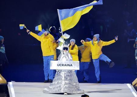 　ミラノ・コルティナ冬季五輪の開会式で、プラカードを持ってウクライナ選手団を先導するロシア人のクチェロワさん＝６日、イタリア・ミラノ（共同）