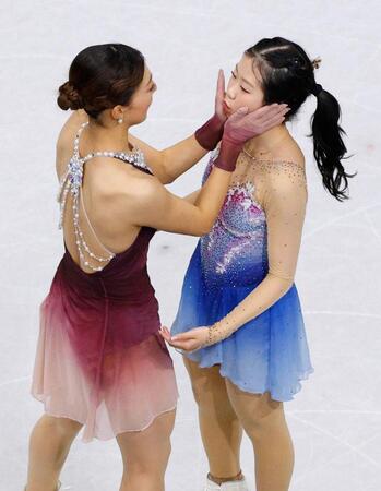 女子の表彰式を前に、坂本花織（左）に頰を挟まれる中井亜美＝ミラノ（共同）