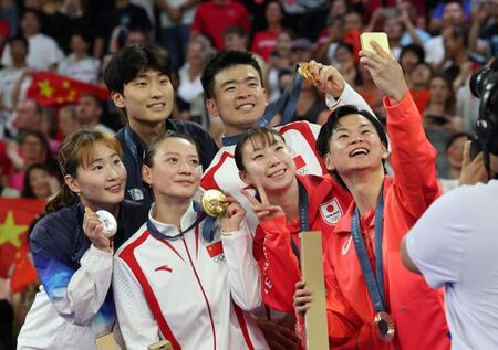 　表彰台で笑顔を見せる渡辺勇大（右）と東野有紗らバドミントン代表の選手たち