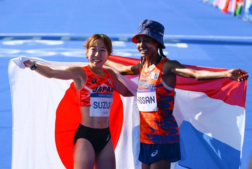 　女子マラソンで優勝したオランダのハッサン（右）と日の丸を広げてポーズをとる６位の鈴木優花（共同）