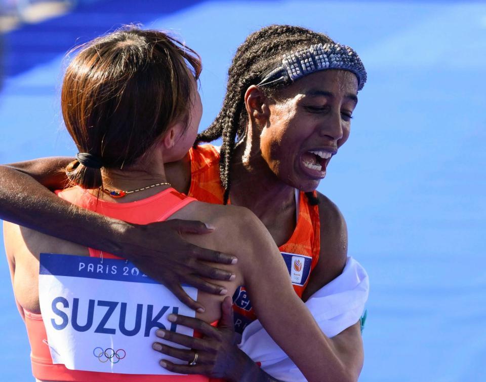 　女子マラソンで優勝し、鈴木優花（左）と健闘をたたえ合うオランダのハッサン（共同）