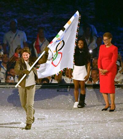 　パリ五輪の閉会式に登場し五輪旗を掲げるトム・クルーズさん。左からシモーネ・バイルズ、ロサンゼルスのバス市長（共同）