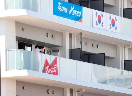 韓国選手団が五輪選手村の居住棟に掲げた応援幕を撤去する関係者＝17日、東京・晴海（聯合＝共同）