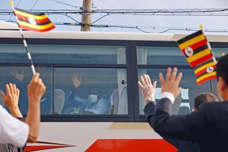 　バスの中から見送りの関係者に手を振る東京五輪のウガンダ選手団のメンバー＝２０日午前、大阪府泉佐野市