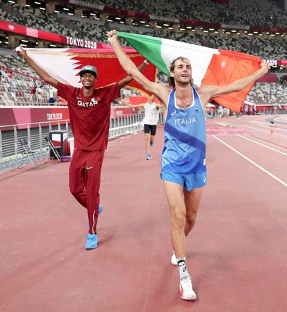 　陸上男子走り高跳びの競技を終え、国旗を掲げるカタールのムタズエサ・バルシム（左）とイタリアのジャンマルコ・タンベリ。金メダルを分け合った（ＡＰ＝共同）