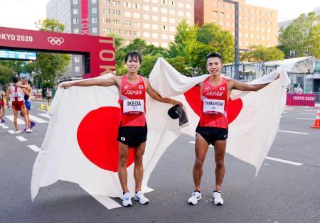 　陸上の男子２０キロ競歩で２位となり、笑顔で日の丸を掲げる池田向希（左）と３位の山西利和＝札幌市