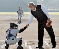 草魂カップの始球式後、捕手を務めた選手と握手する鈴木啓示さん＝西脇公園野球場