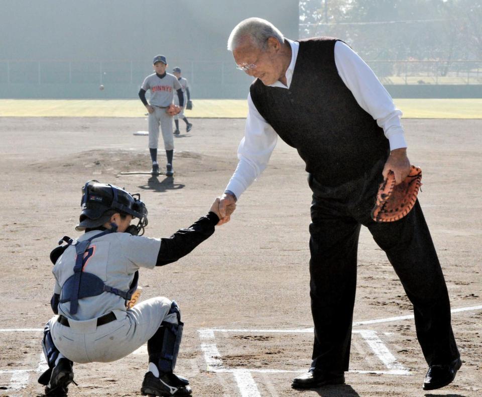 草魂カップの始球式後、捕手を務めた選手と握手する鈴木啓示さん＝西脇公園野球場