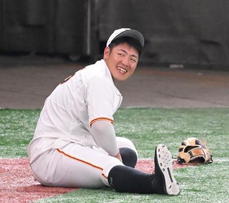 試合前の練習中に笑顔を見せる巨人・岡本和