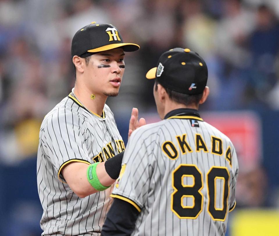 阪神・岡田彰布監督（右）とタッチを交わす阪神・佐藤輝明＝２３年１０月２８日