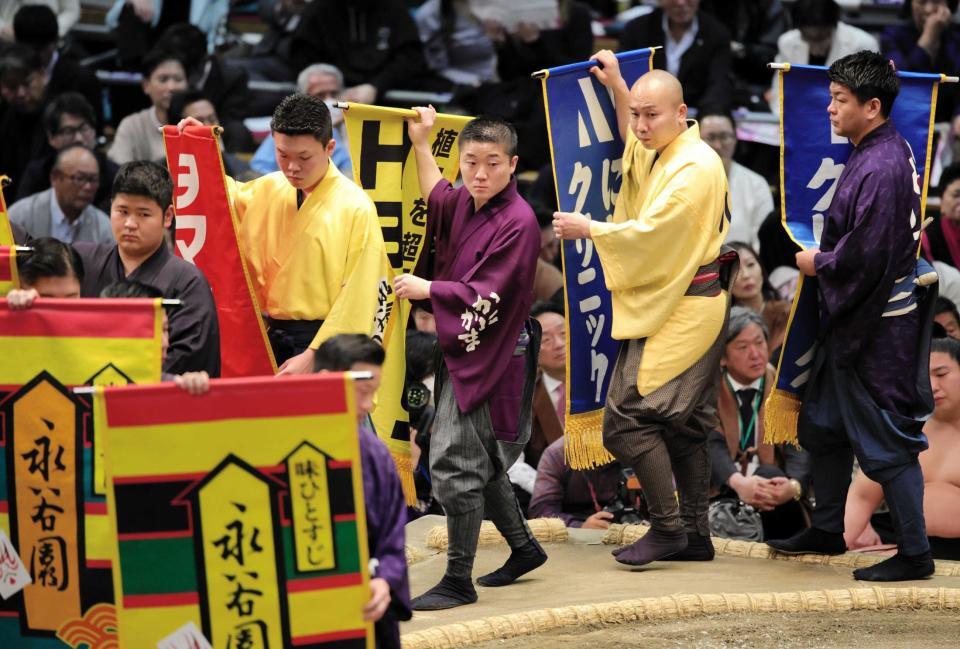 　懸賞を持って土俵をまわる呼び出しの大将（中央）＝２２日、エディオンアリーナ大阪