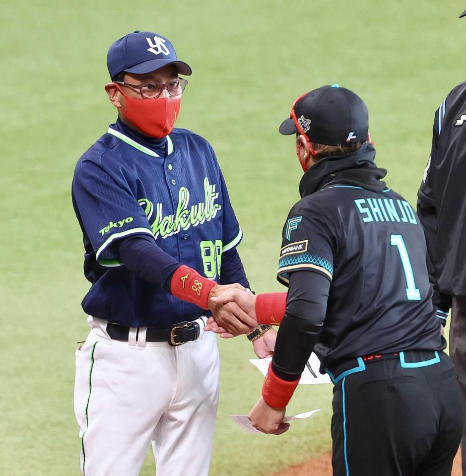 　新庄監督（１）からプレゼントされた赤いマスク姿で握手を交わす池山監督＝３月２２日