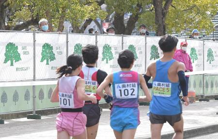 周回コースと公園を仕切ったフェンスの上から、レースの様子をのぞき込む人々＝１月31日、長居公園（撮影・高部洋祐）