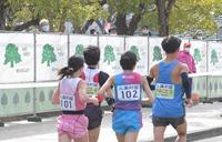 周回コースと公園を仕切ったフェンスの上から、レースの様子をのぞき込む人々＝１月31日、長居公園（撮影・高部洋祐）